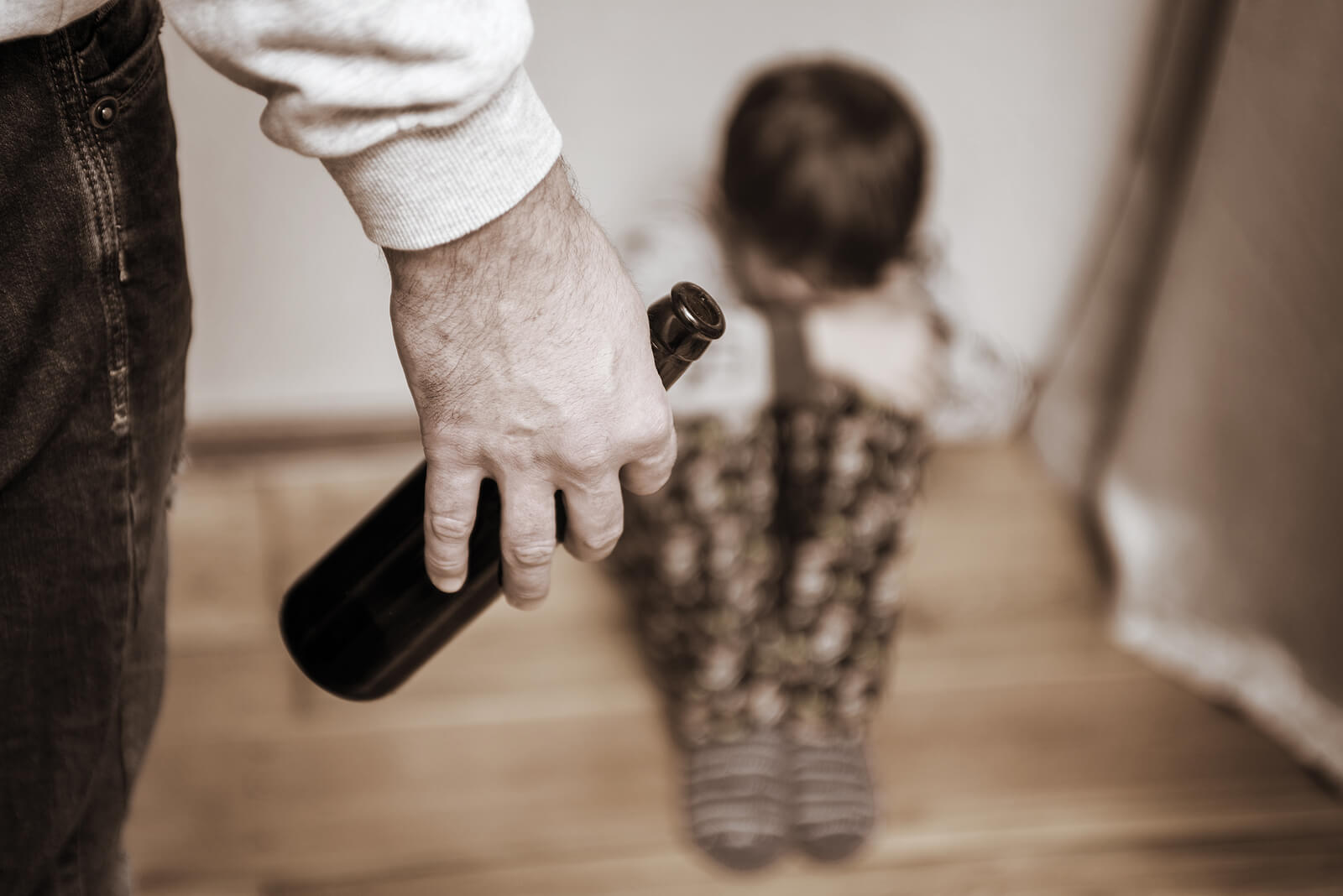 Hijo de padre alcohólico asustado en el suelo.