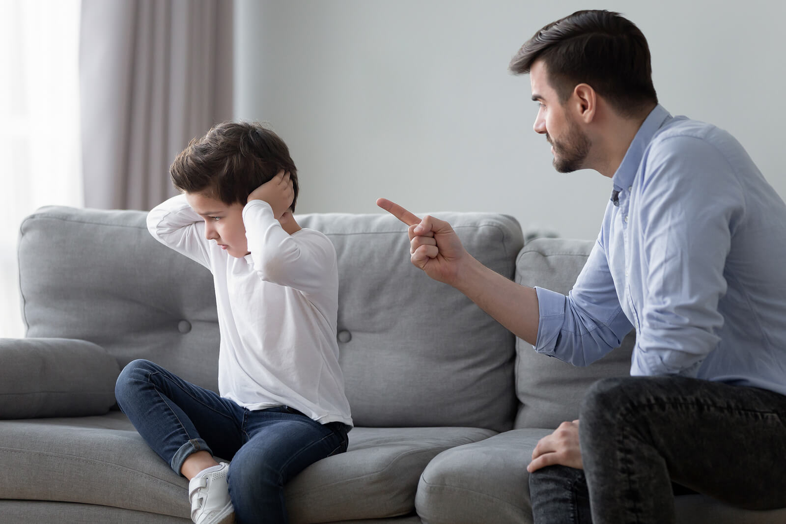 Padre autoritario regañando a su hijo.