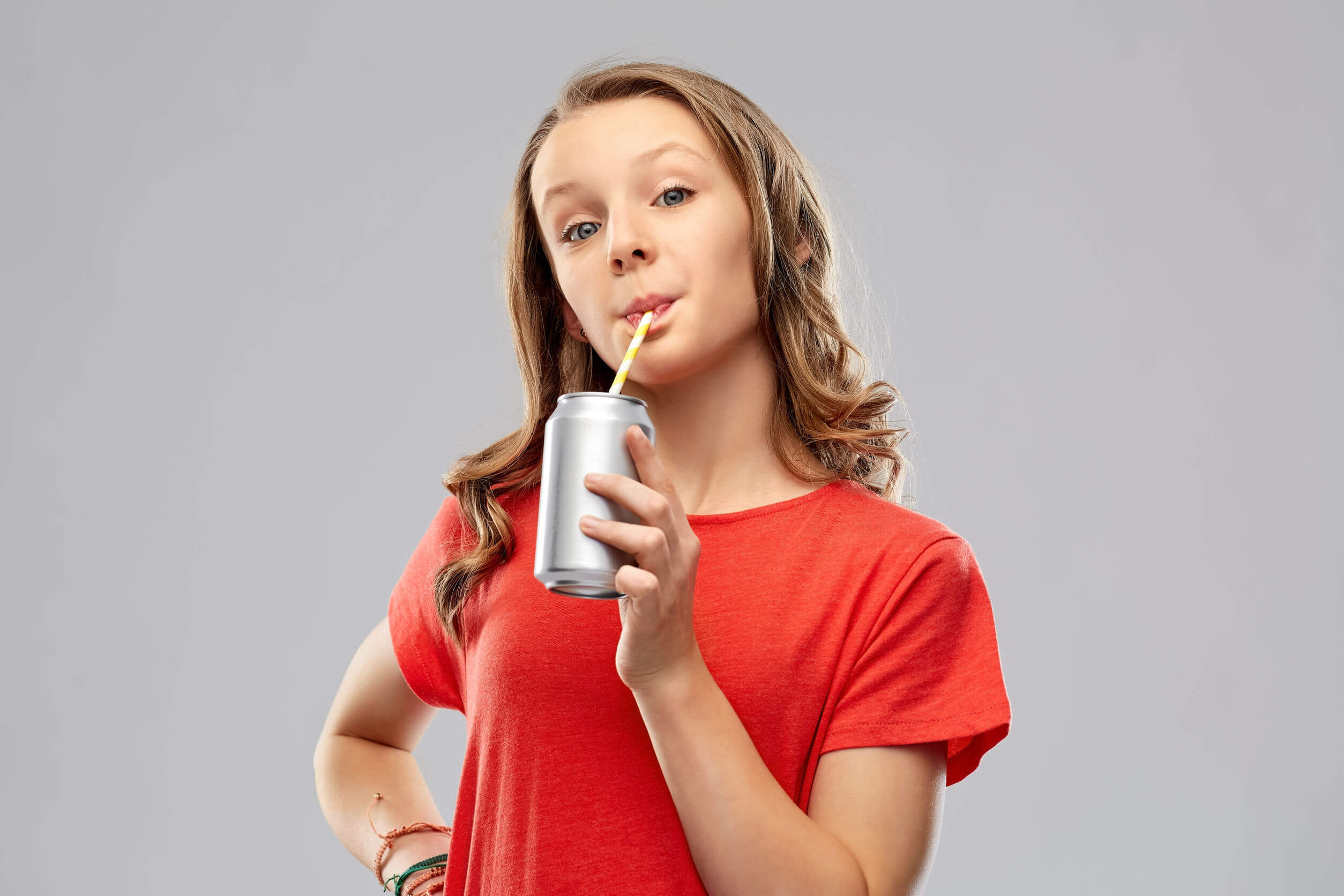 Chica adolescente bebiendo un refresco con muchos carbohidratos y azúcar.