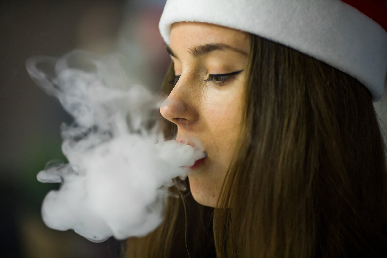 Chica adolescente soltando el humo del cigarro.