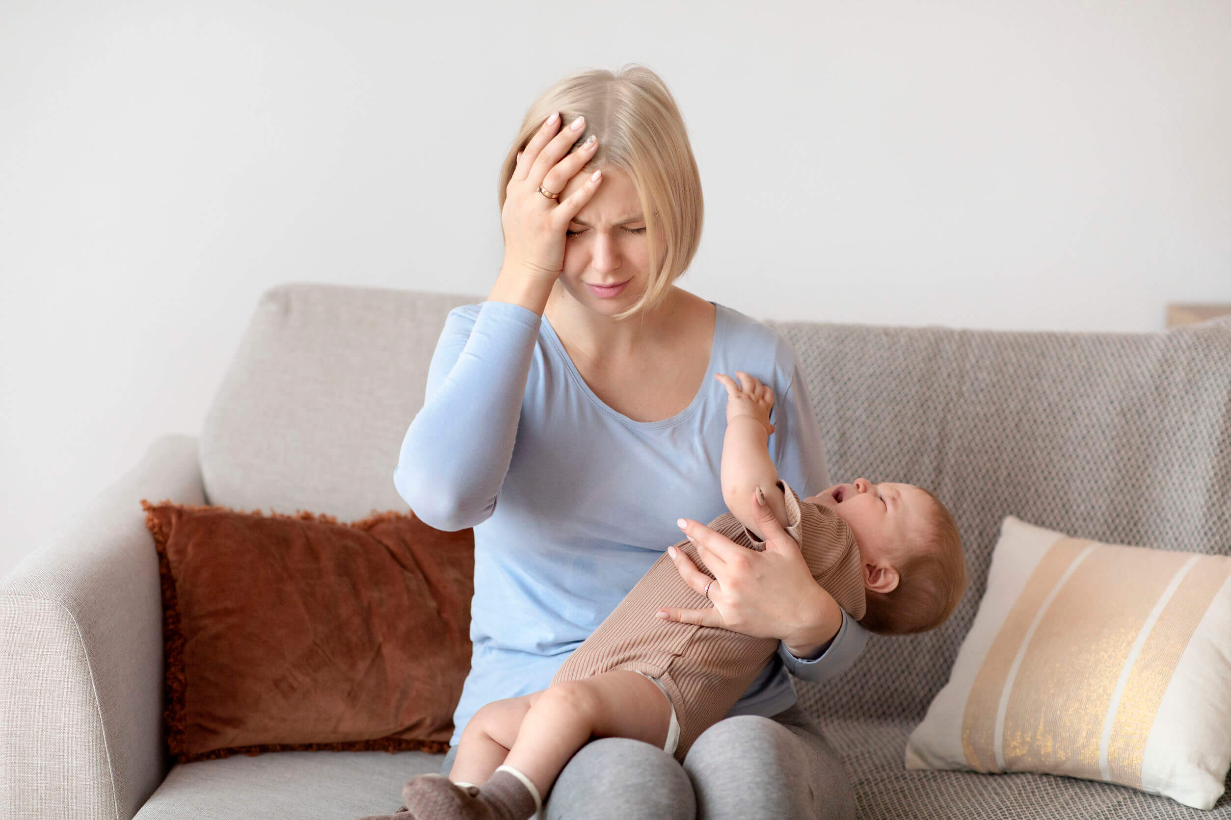 Mère fatiguée avec son bébé qui pleure dans ses bras.