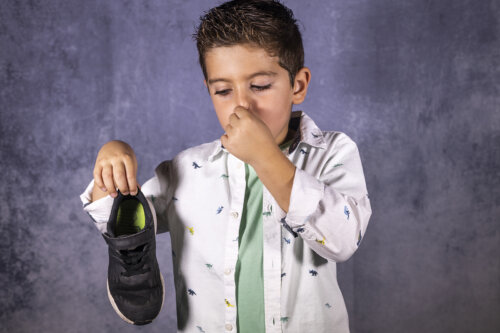 Niño con la nariz tapada debido al mal olor de sus pies y sus zapatos.