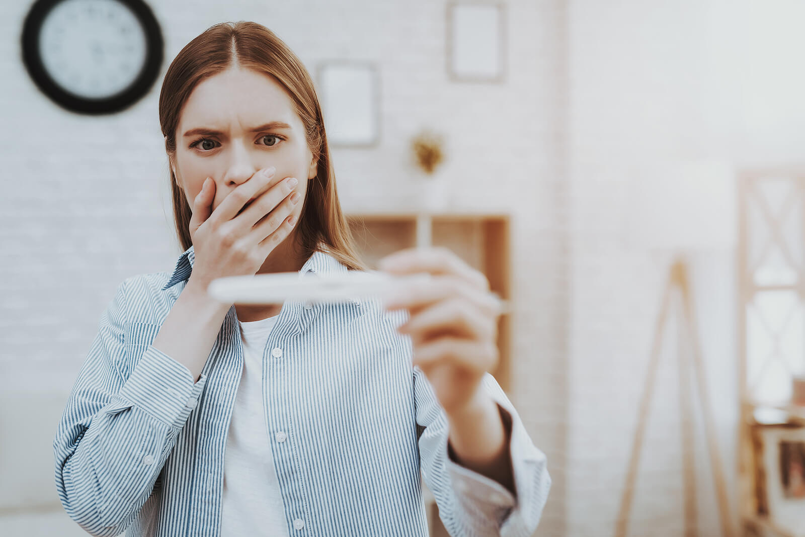 Mujer sorprendida con un test de embarazo positivo en la mano porque sufre tocofobia.