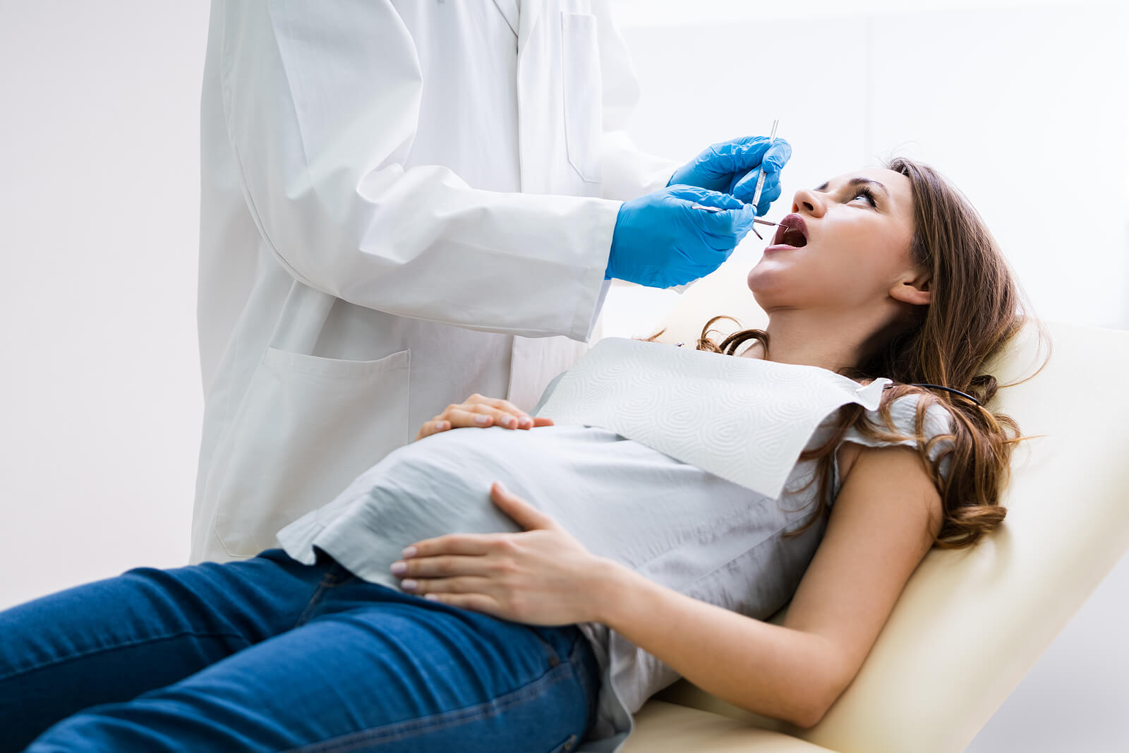 A dentist working on a pregnant woman's teeth.