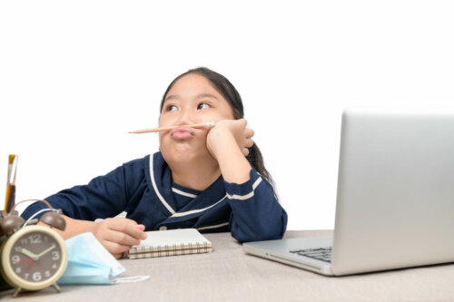 Niña muy distraída haciendo malabares con un lápiz sobre los labios.