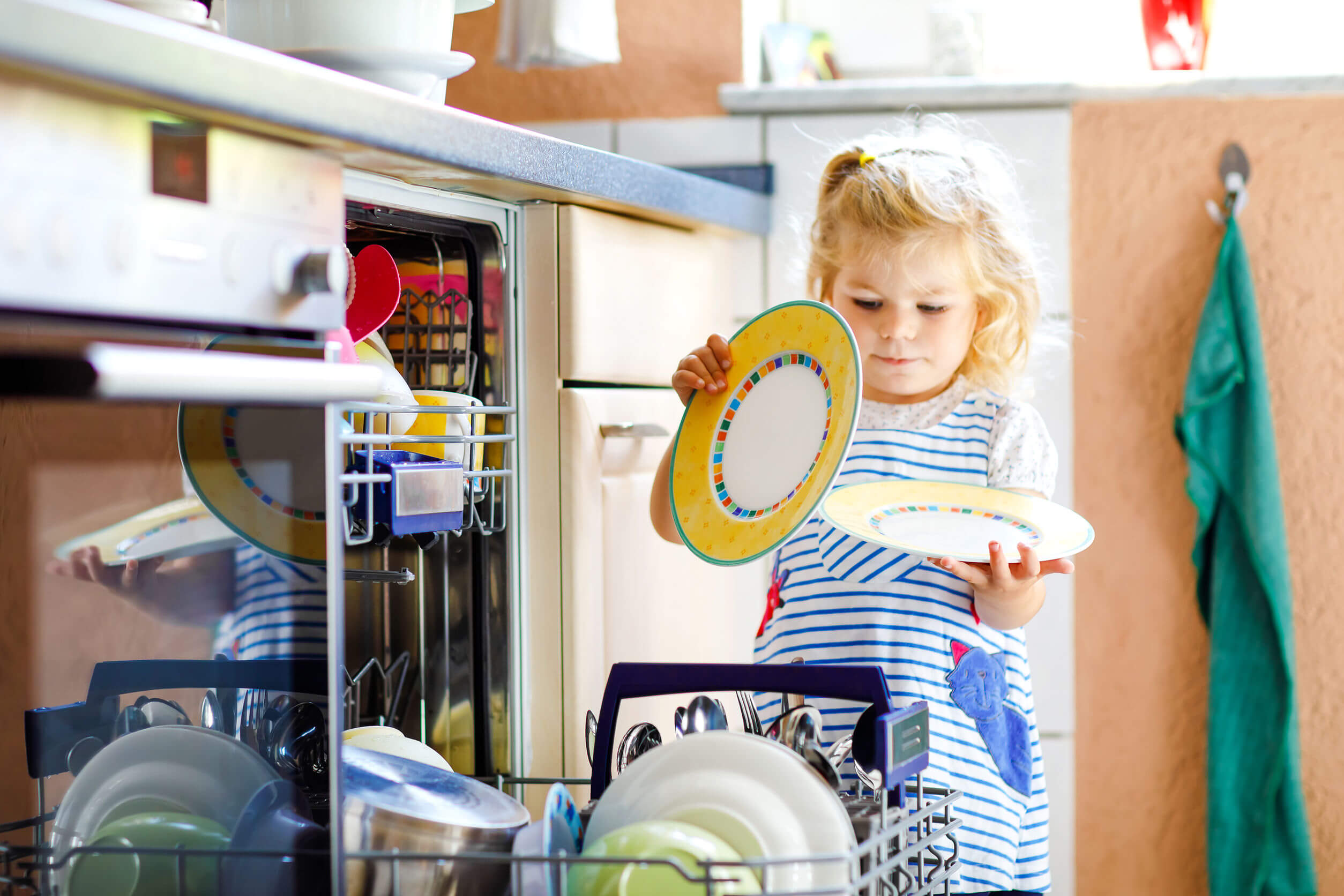 A toddler helping to unload the dishwasher.