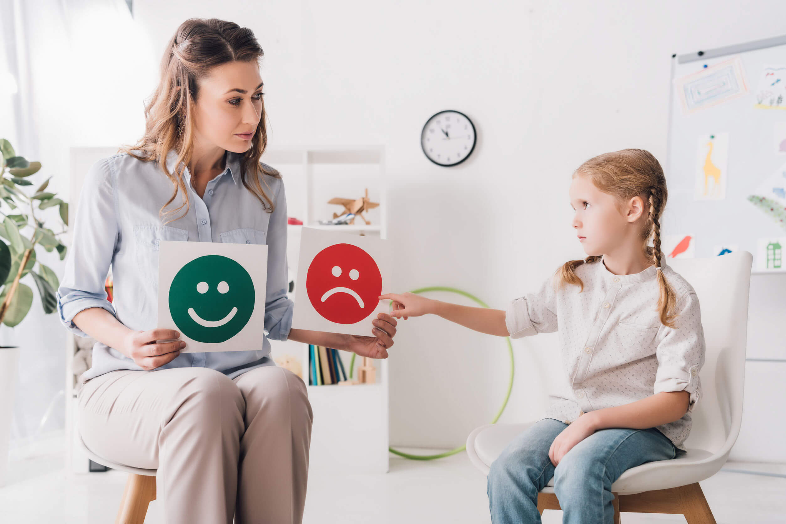 A child pointing to a picture of a sad face with a therapist. 