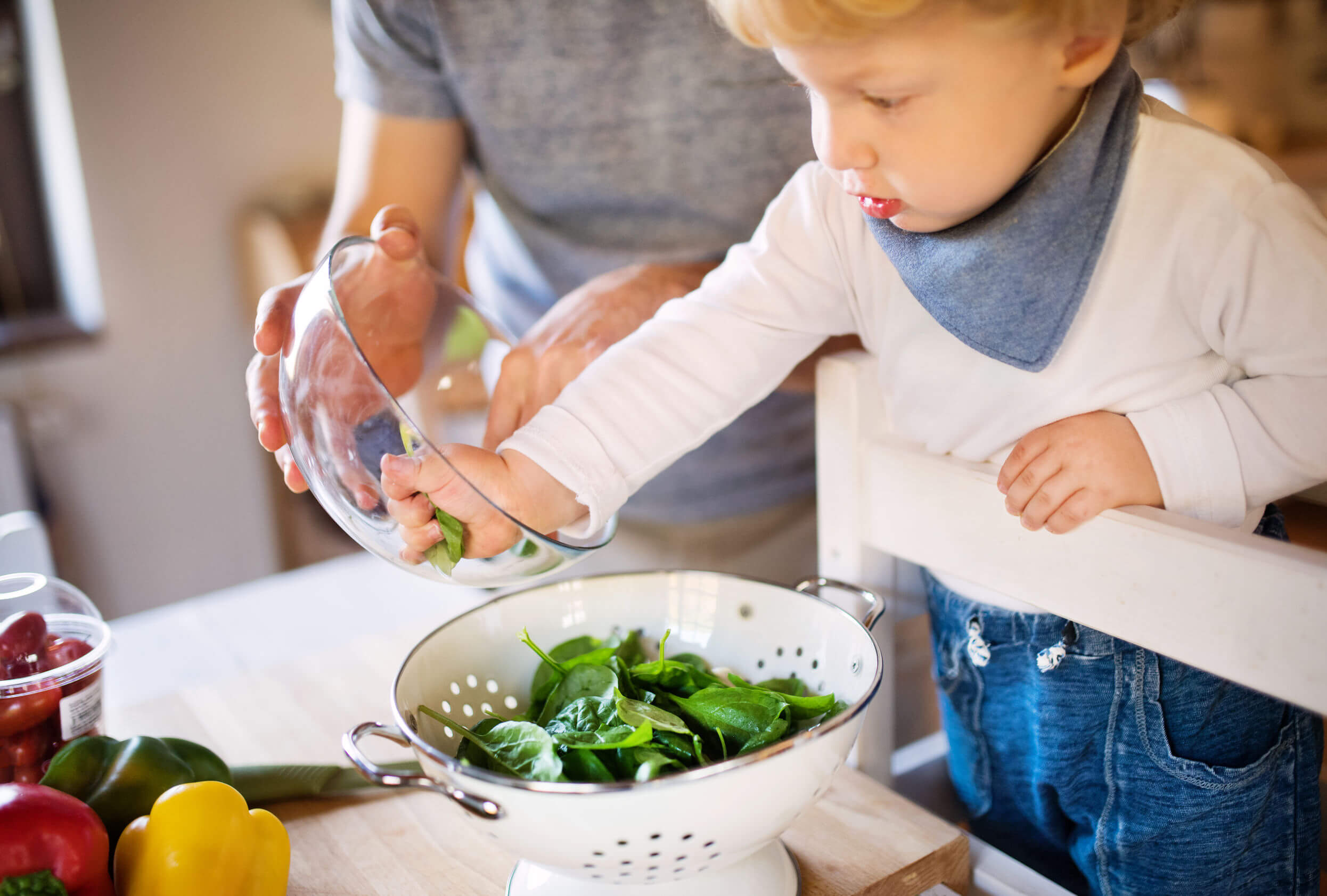 Niño ayudando a su padre en la cocina debido a los beneficios infantiles que tienen cocinar con los padres.