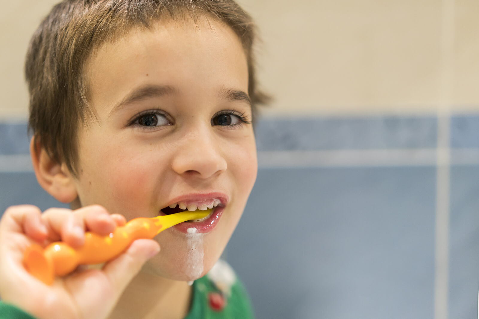 Niño lavándose los dientes con una pasta con flúor.