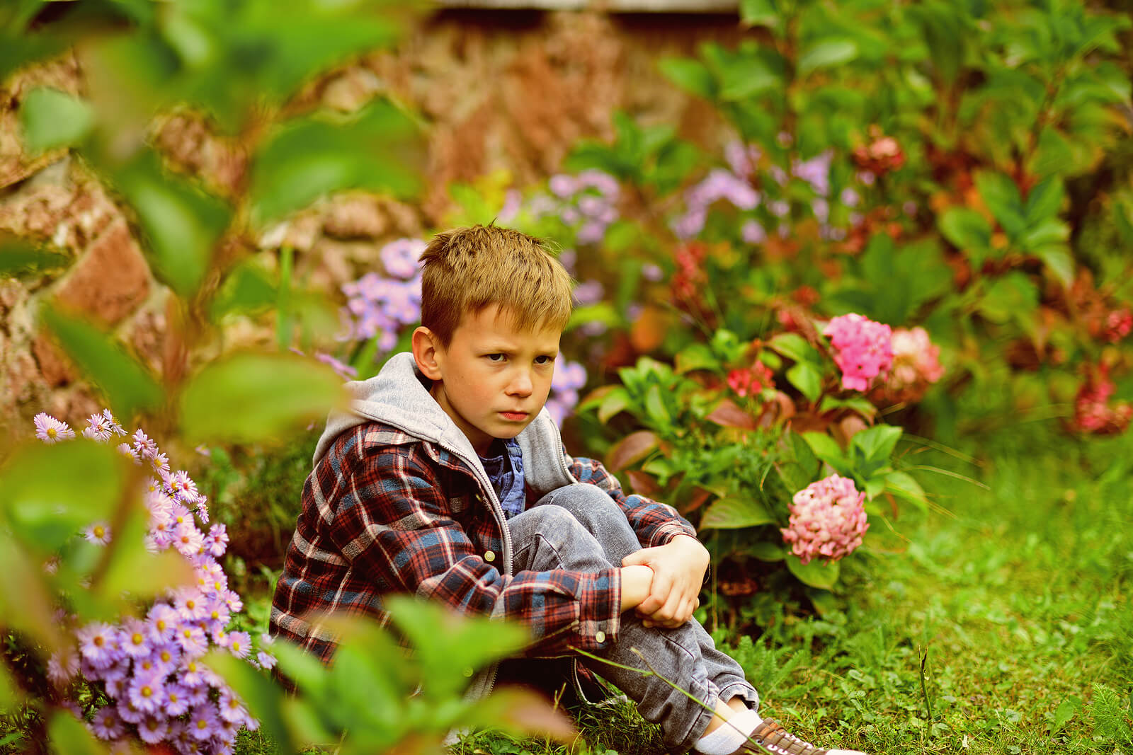 Un enfant en colère assis dans l'herbe.