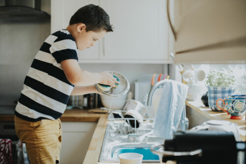 Niño fregando los platos después de comer.