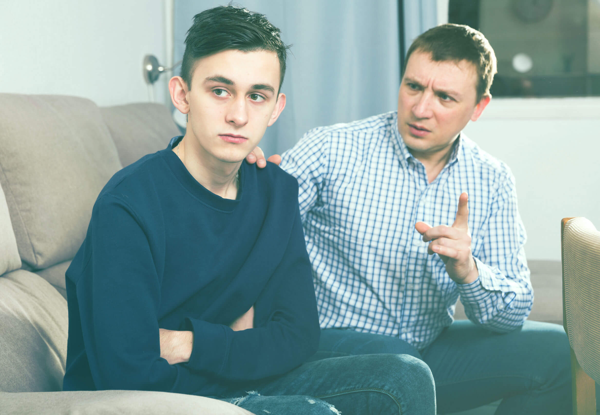 A teen boy looking away as his father lectures him.