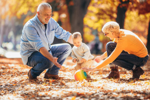 Abuelos jugando con su nieto en el parque en otoño.