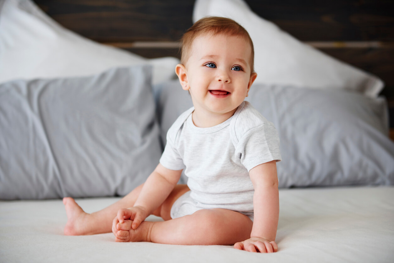 Un bébé assis dans un grand lit.