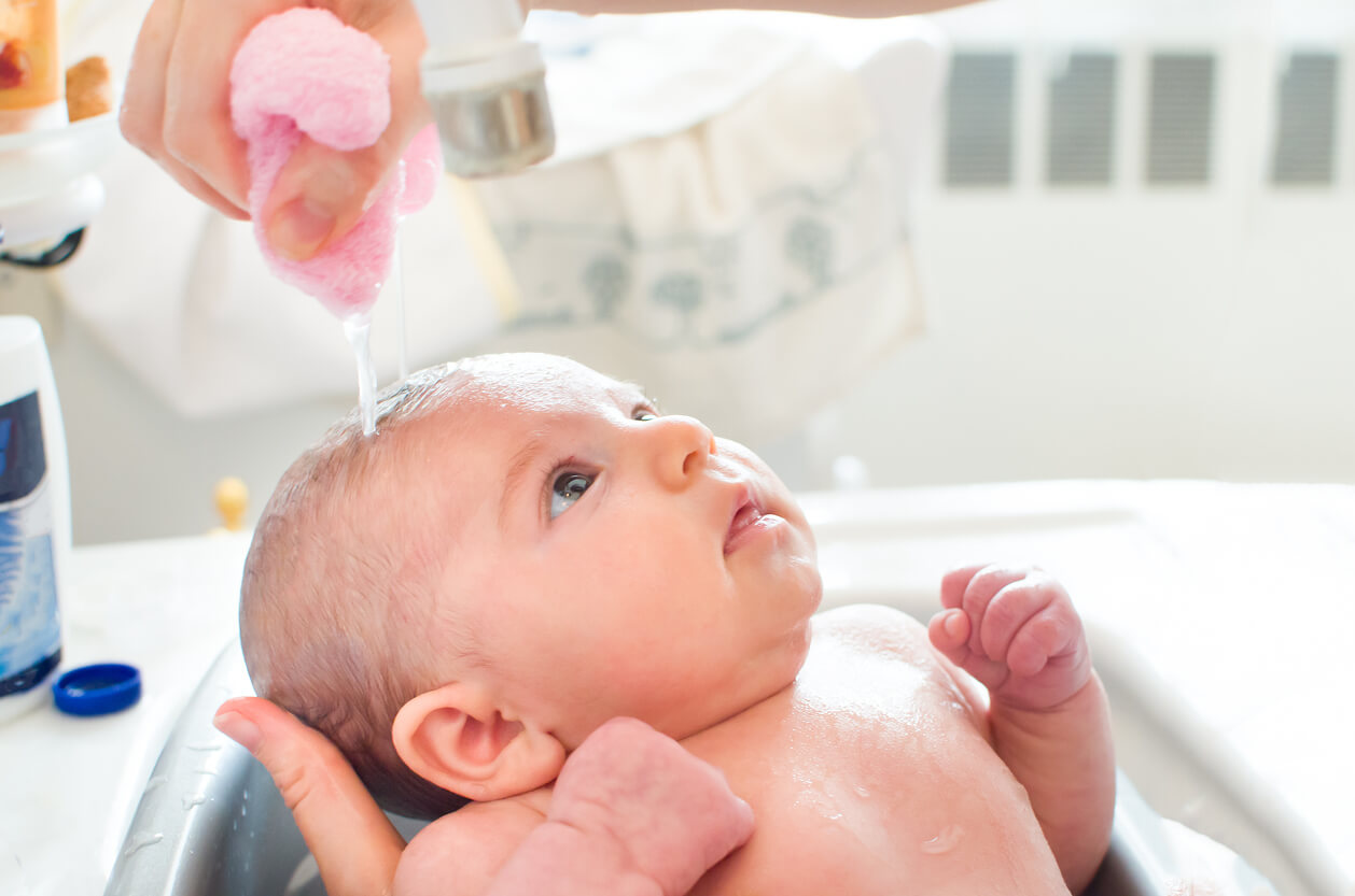 Padre lavando el pelo de su bebé.