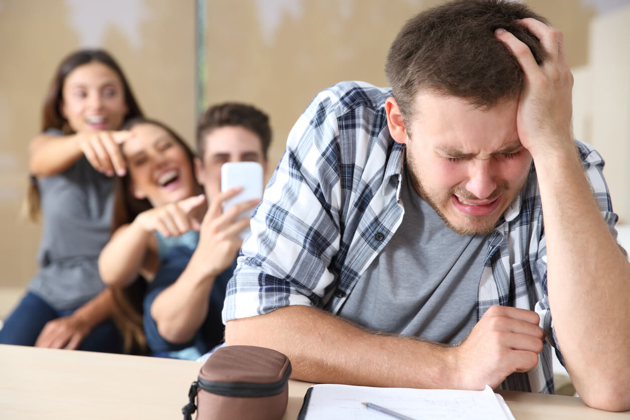 Chico adolescente sufriendo bullying por parte de sus compañeros.