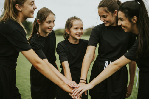 Equipo femenino uniendo sus manos.