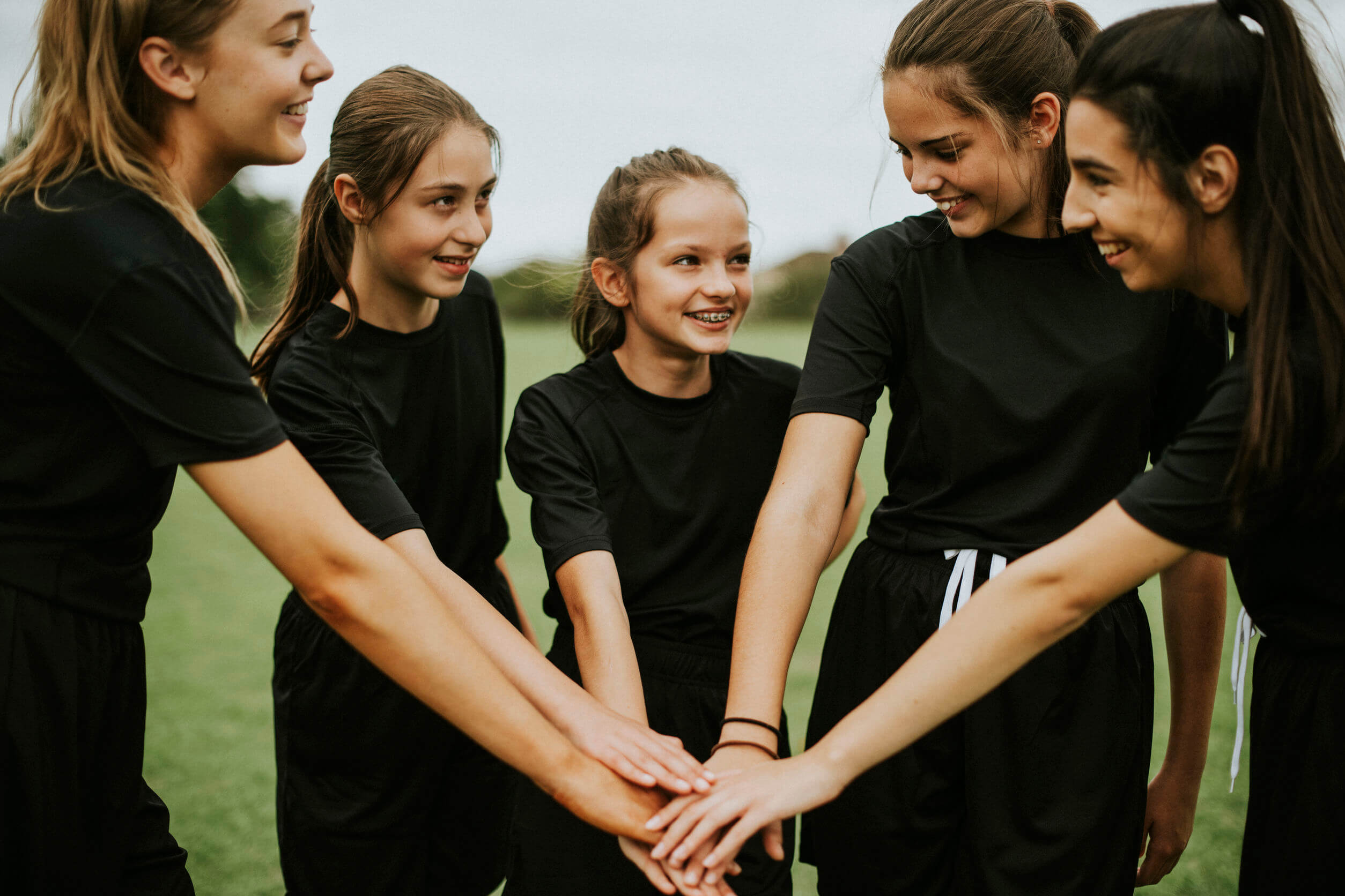 Equipo femenino uniendo sus manos.