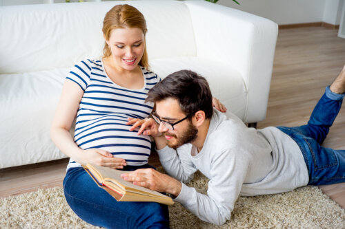 Padre leyendo un libro a la barriga de su mujer embarazada.