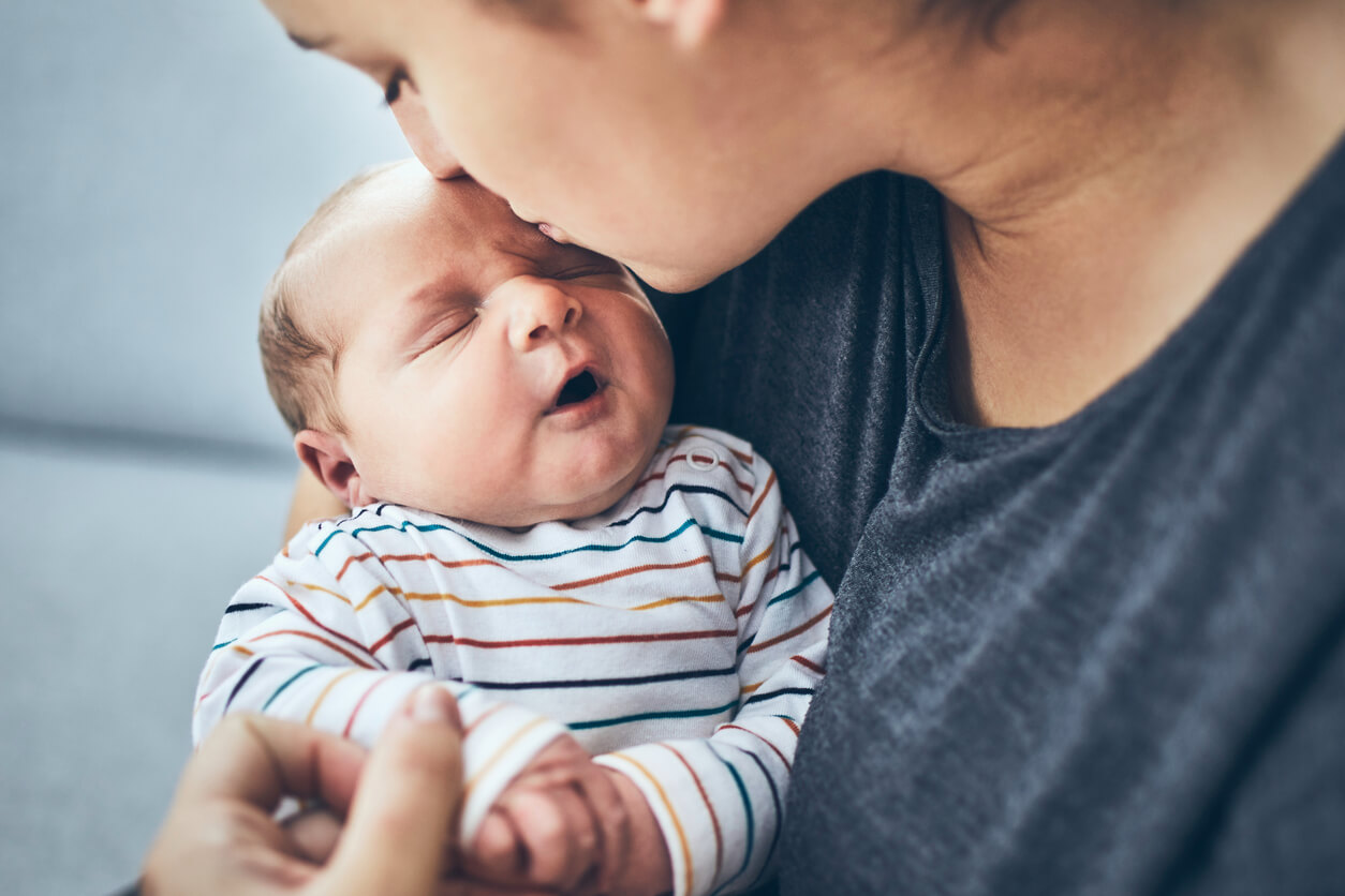 Mère embrassant son bébé sur le front.
