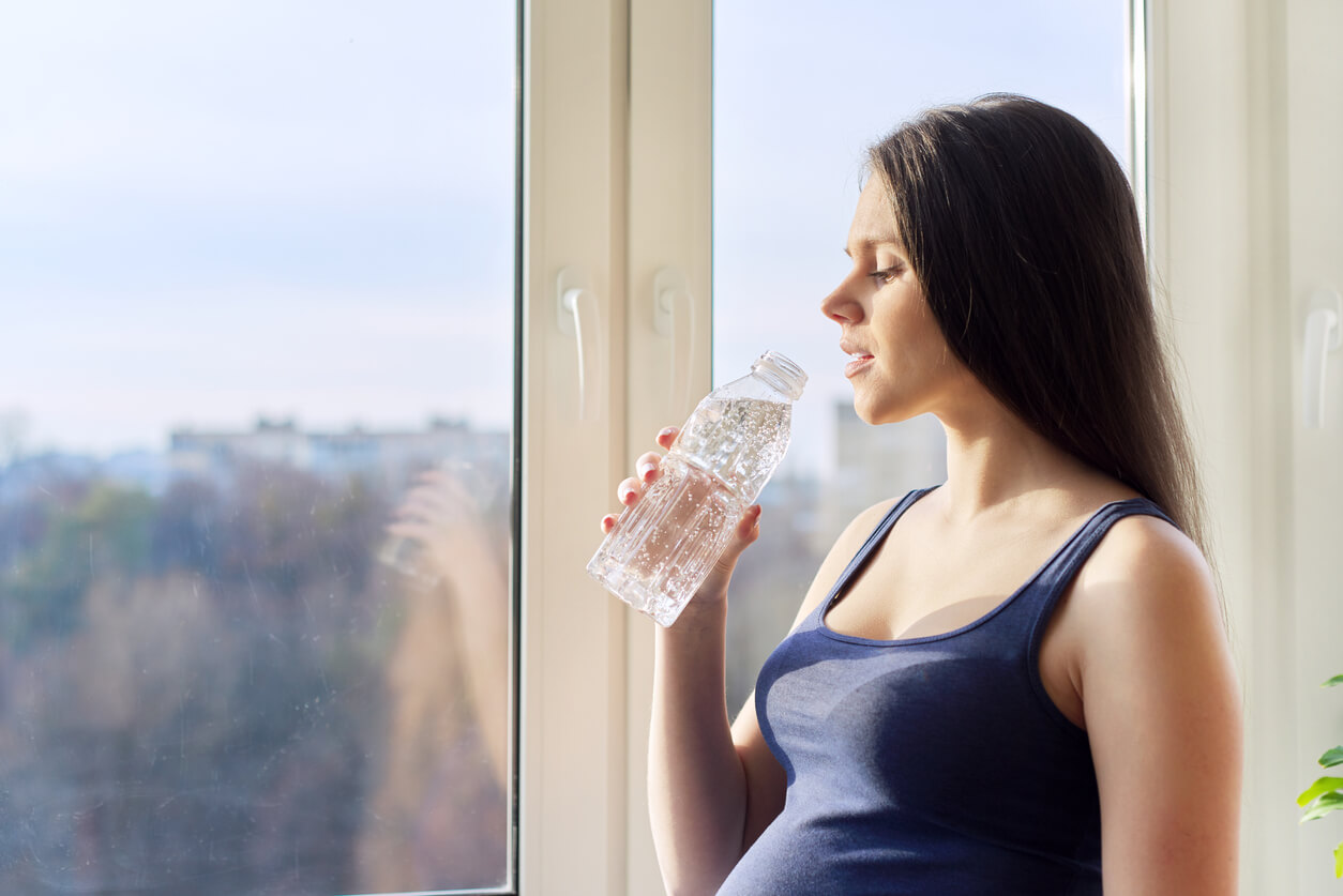 Mujer embarazada bebiendo mucha agua.