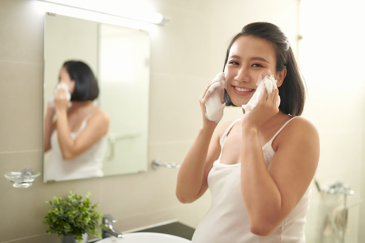 Mujer limpiando su rostro como parte de su rutina de belleza diaria durante el embarazo.