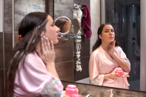 Mujer embarazada aplicando crema hidratante en su rostro.