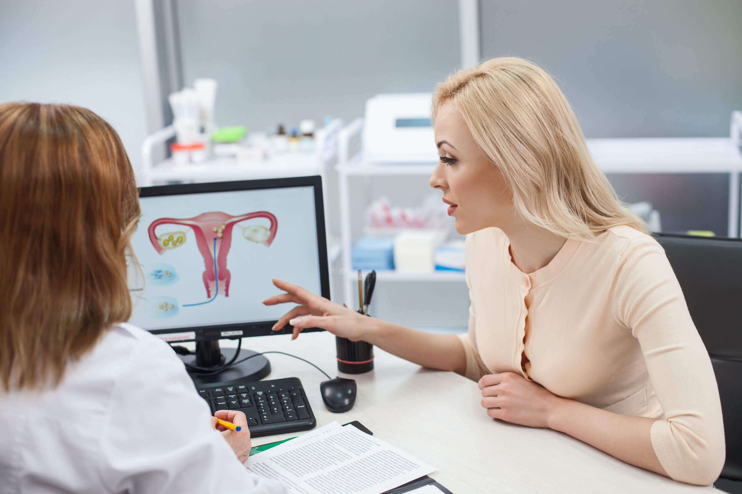 Mujer en el ginecólogo aprendiendo sobre el tamaño de la barriga y el útero durante el embarazo.