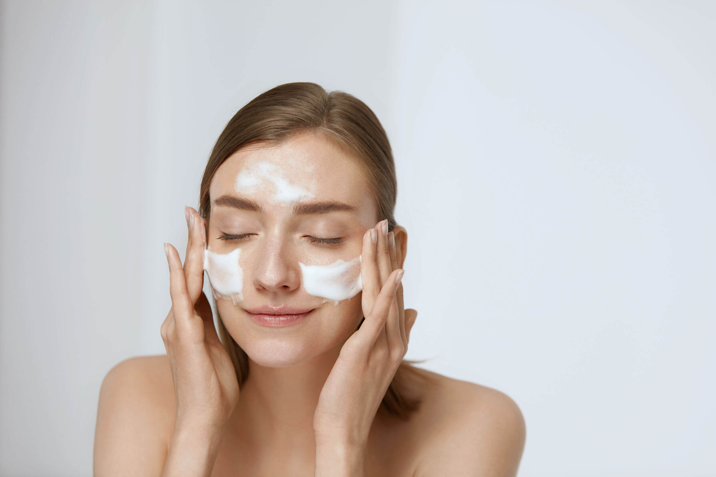 Woman applying a moisturizing cream as part of the facial routine for pregnant women.