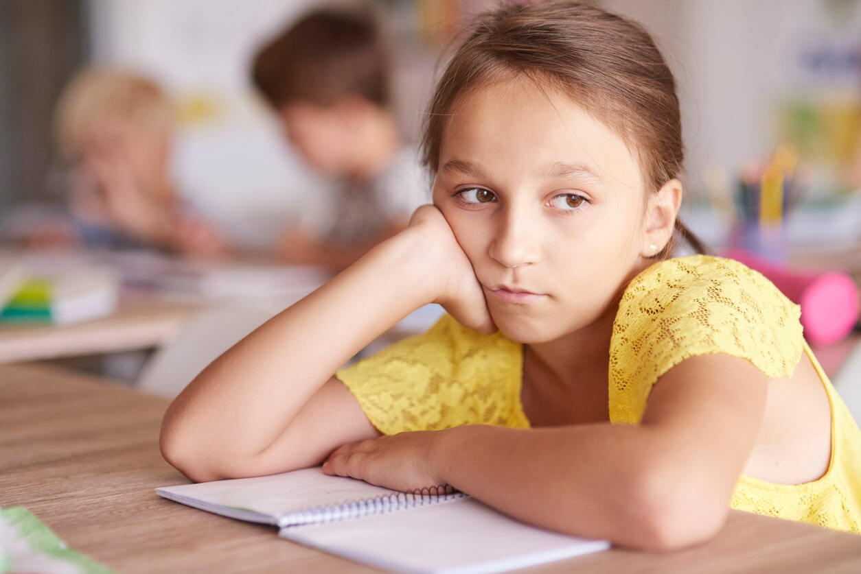 Niña pensando porque se aburre en la escuela.