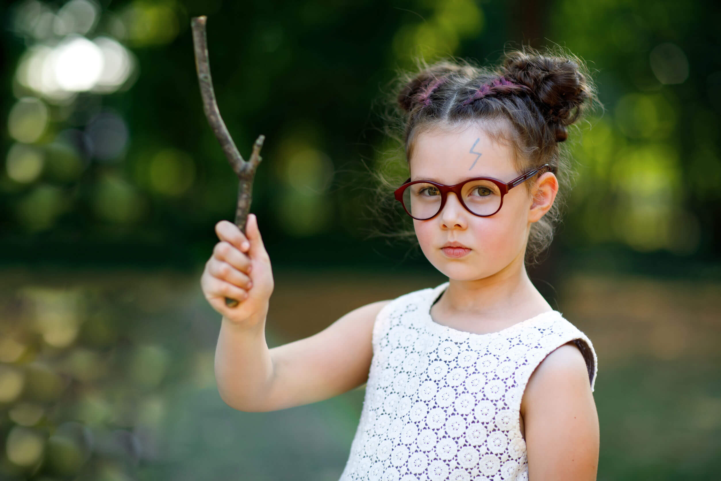 Niña disfrazada de Harry Potter con una varita hecha con un palo.