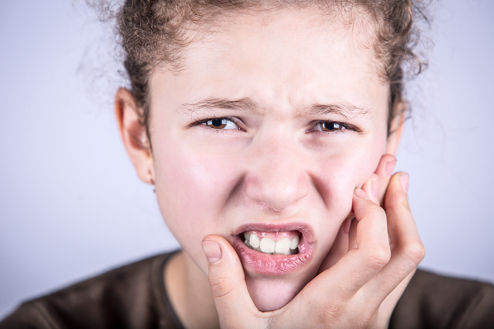 Niña con dolor de dientes debido a que sufre gingivitis.