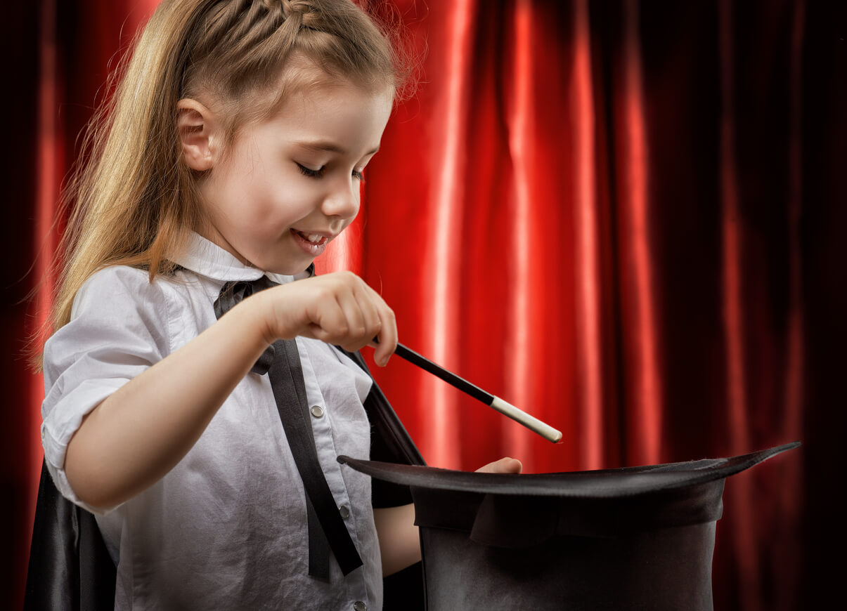 Niña haciendo magia con una chistera.