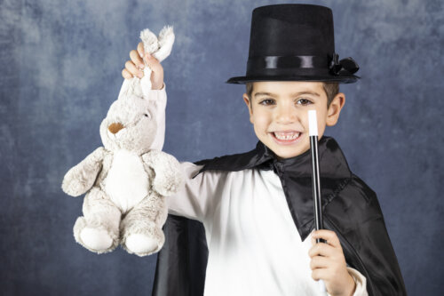 Niño haciendo magia sacando un conejo de la chistera.