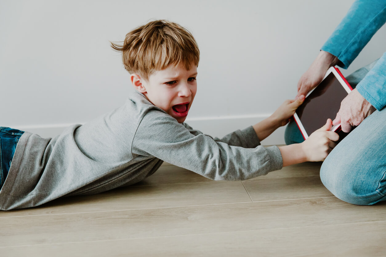 Niño gritando porque su madre le ha quitado la tablet porque intenta educar a sus hijos sin tecnología.