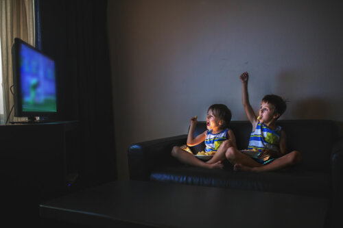 Niños viendo la televisión mientras comen gominolas.