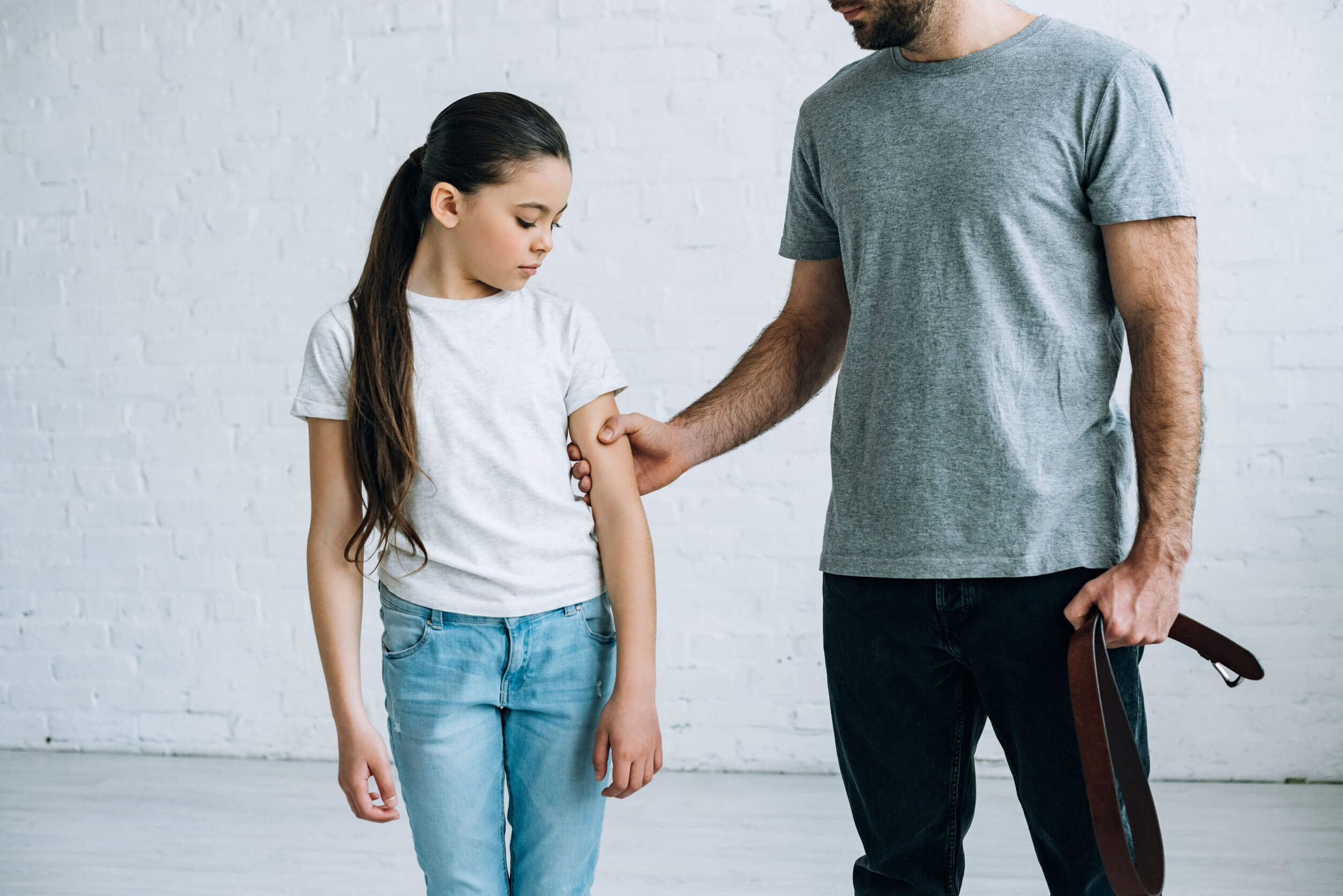 Padre aplicando el castigo físico con su hija.