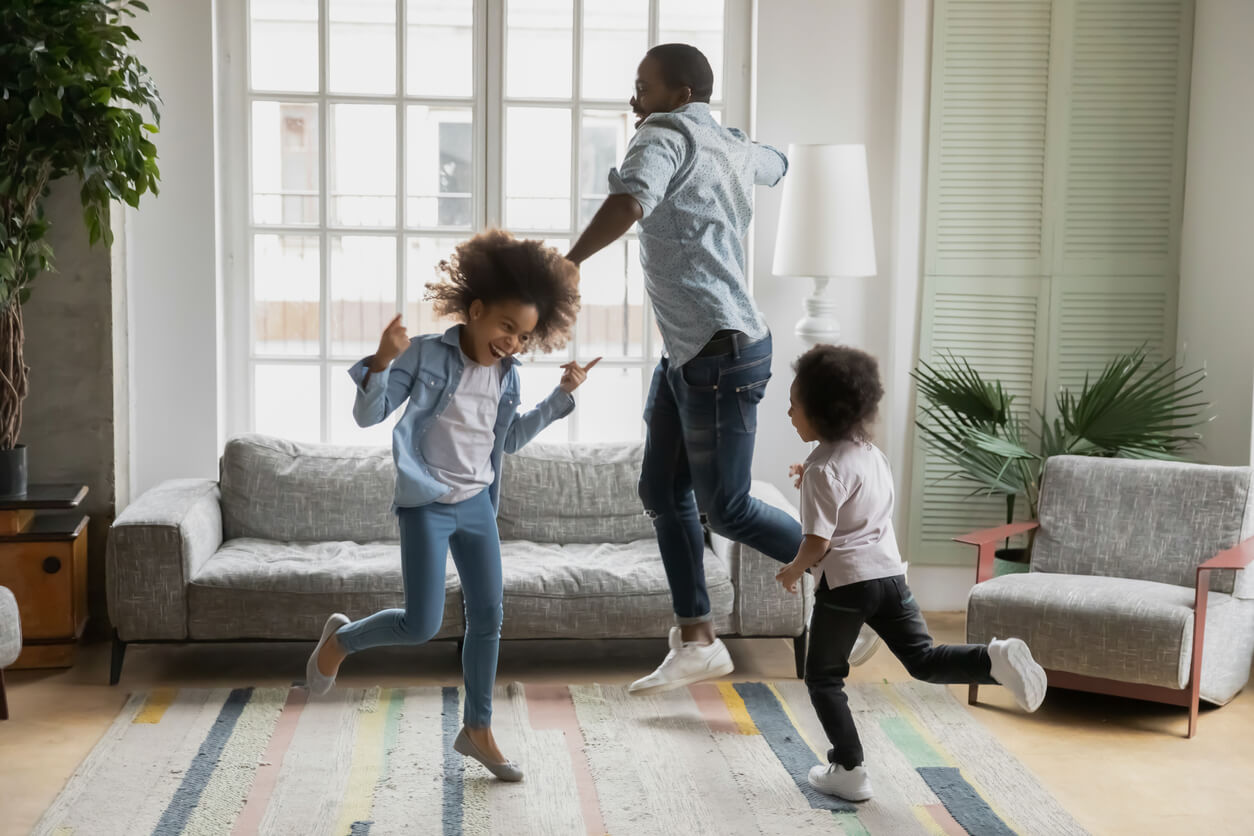 Padre bailando con sus hijos en el salón de casa.