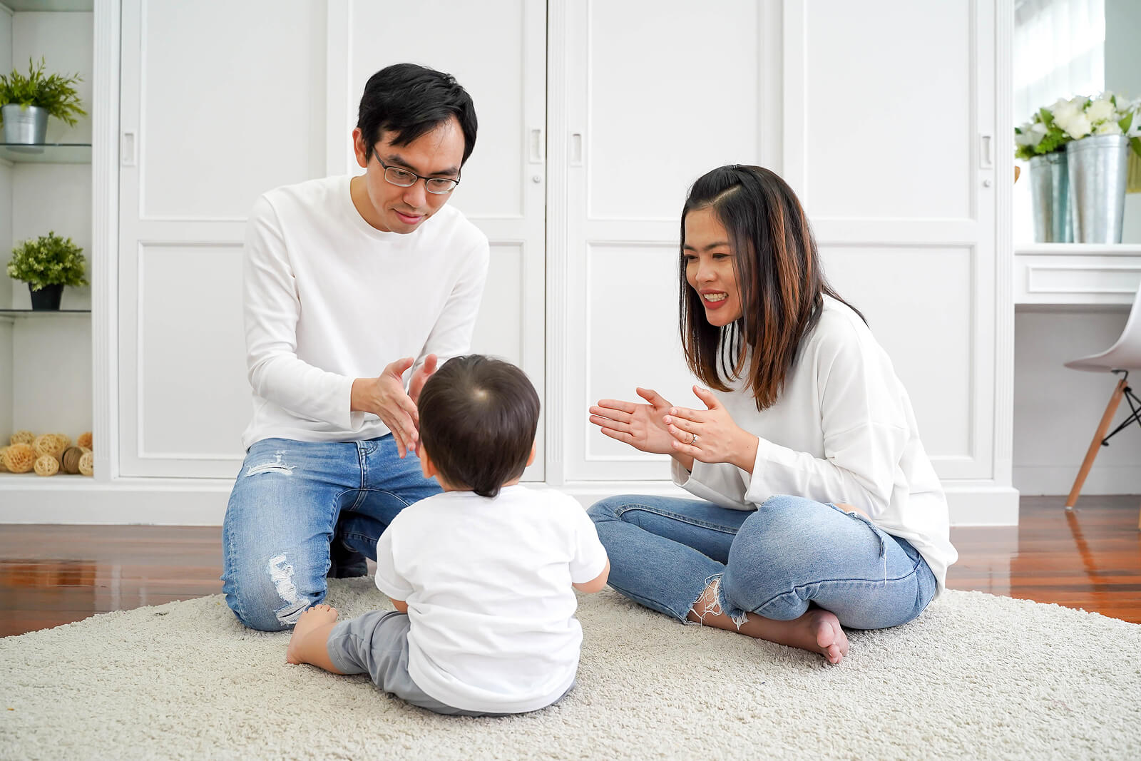 Deux parents qui jouent avec leur enfant à la maison.