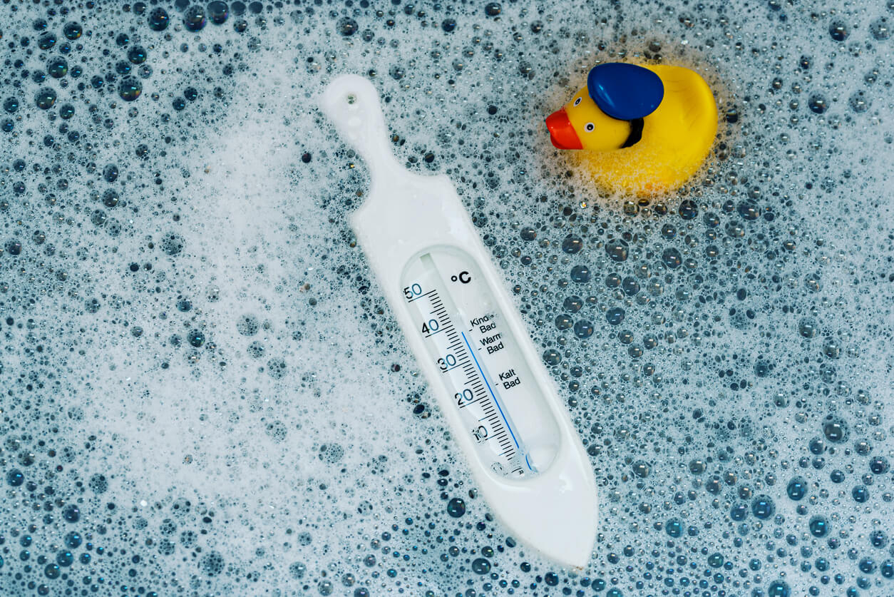 A bath thermometer floating in soapy water.