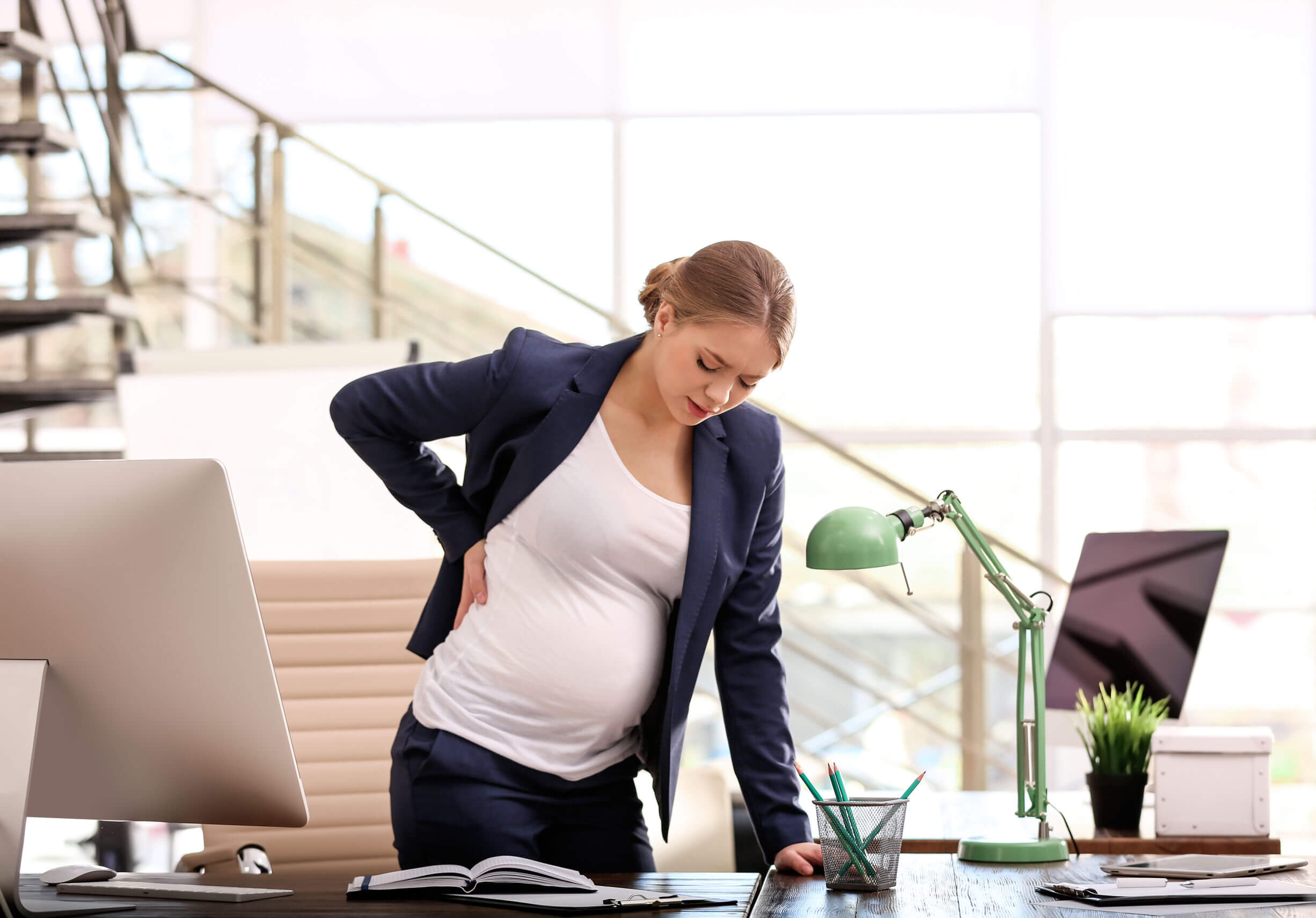 Une femme enceinte au travail qui a mal au dos. 