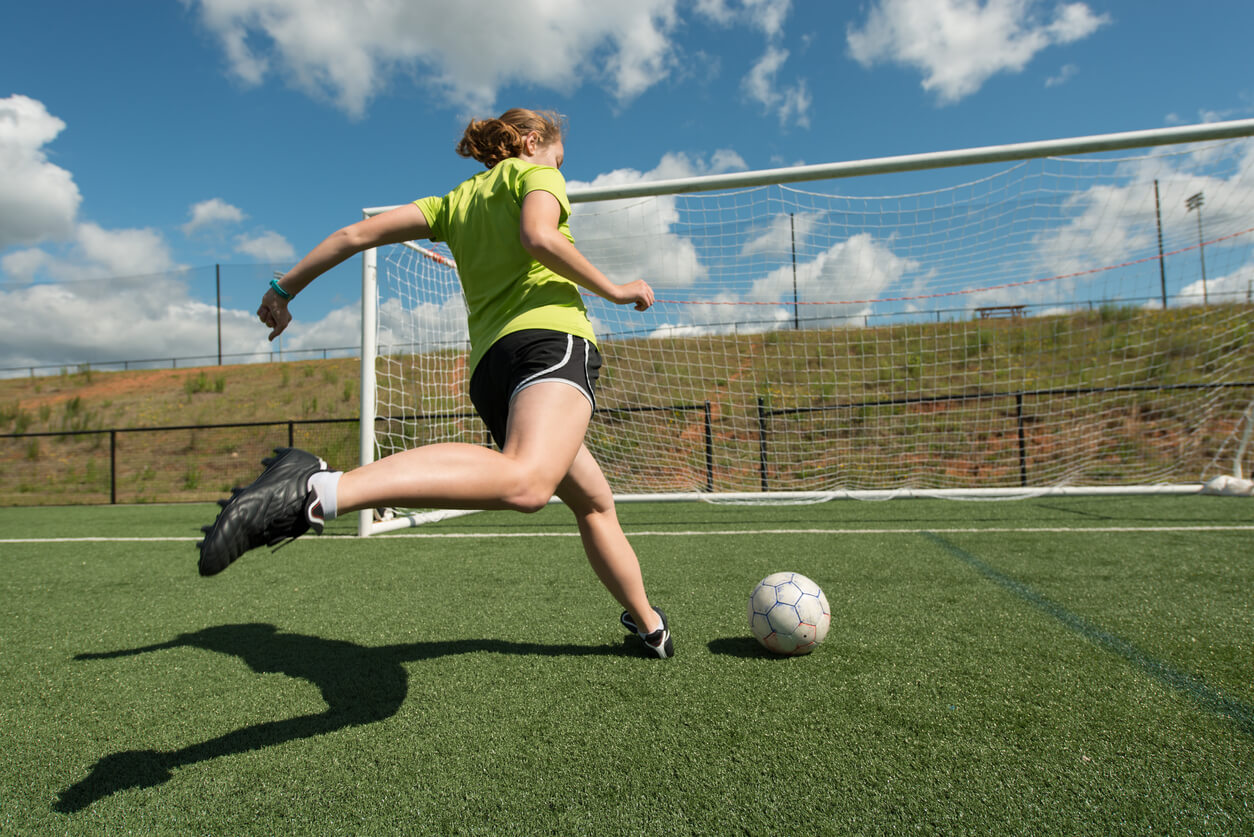 Chica adolescente jugando al fútbol.