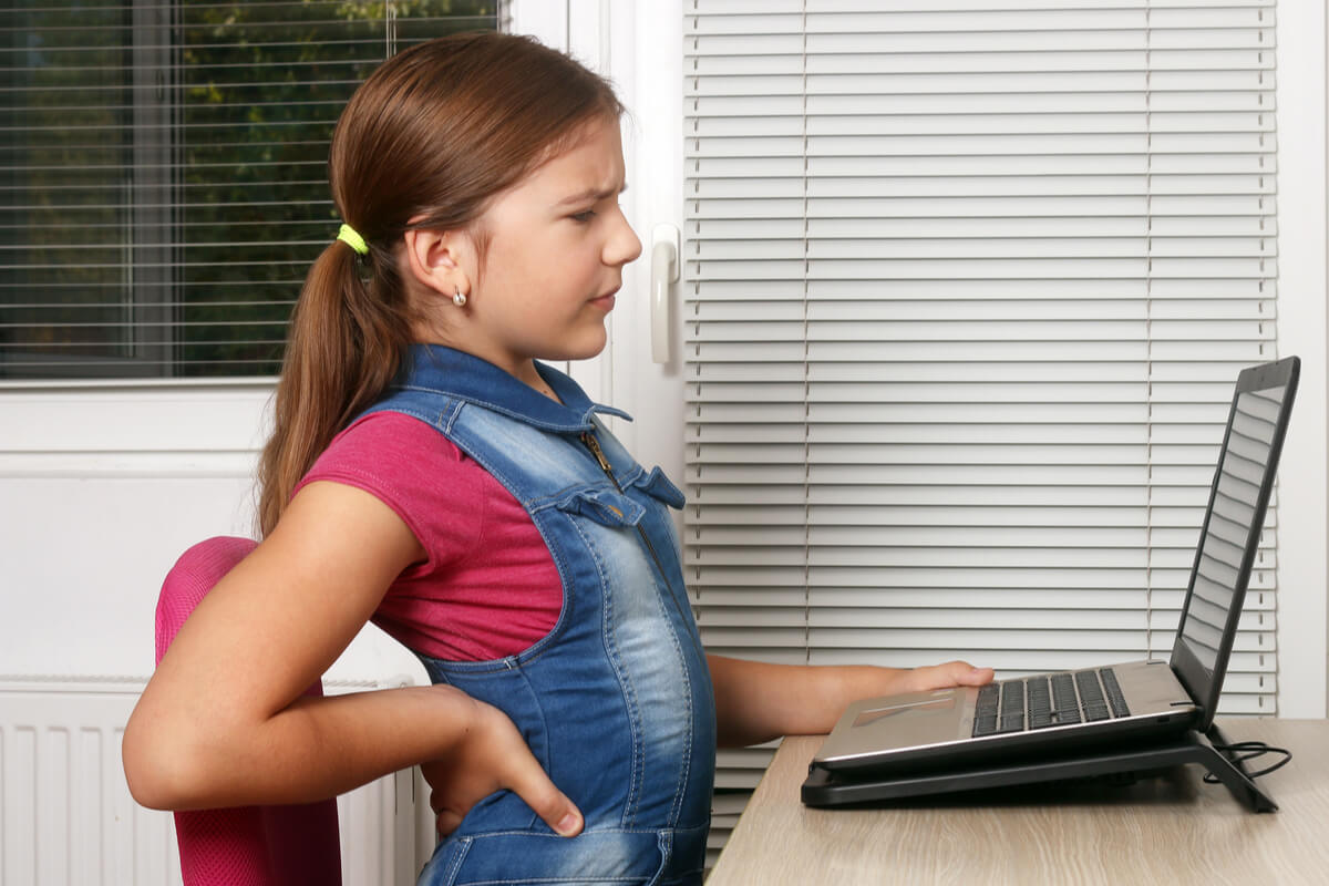Jeune fille souffrant de lombalgie devant son ordinateur. 