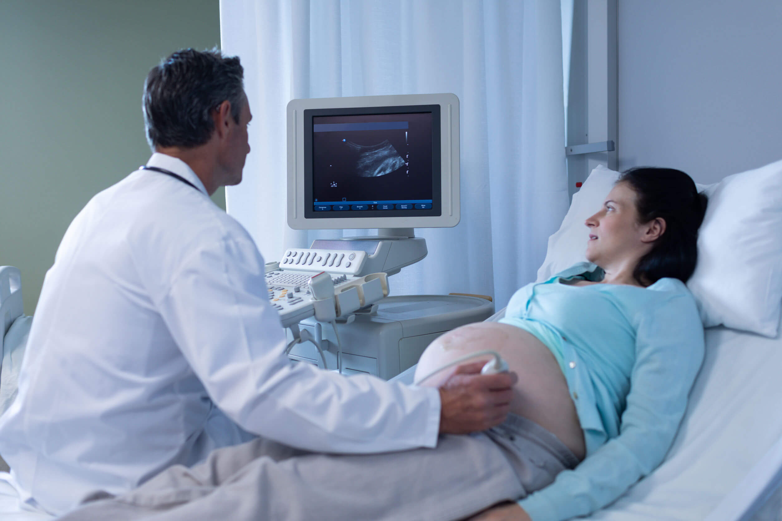 En läkare som utför ett ultraljud på en gravid kvinna.