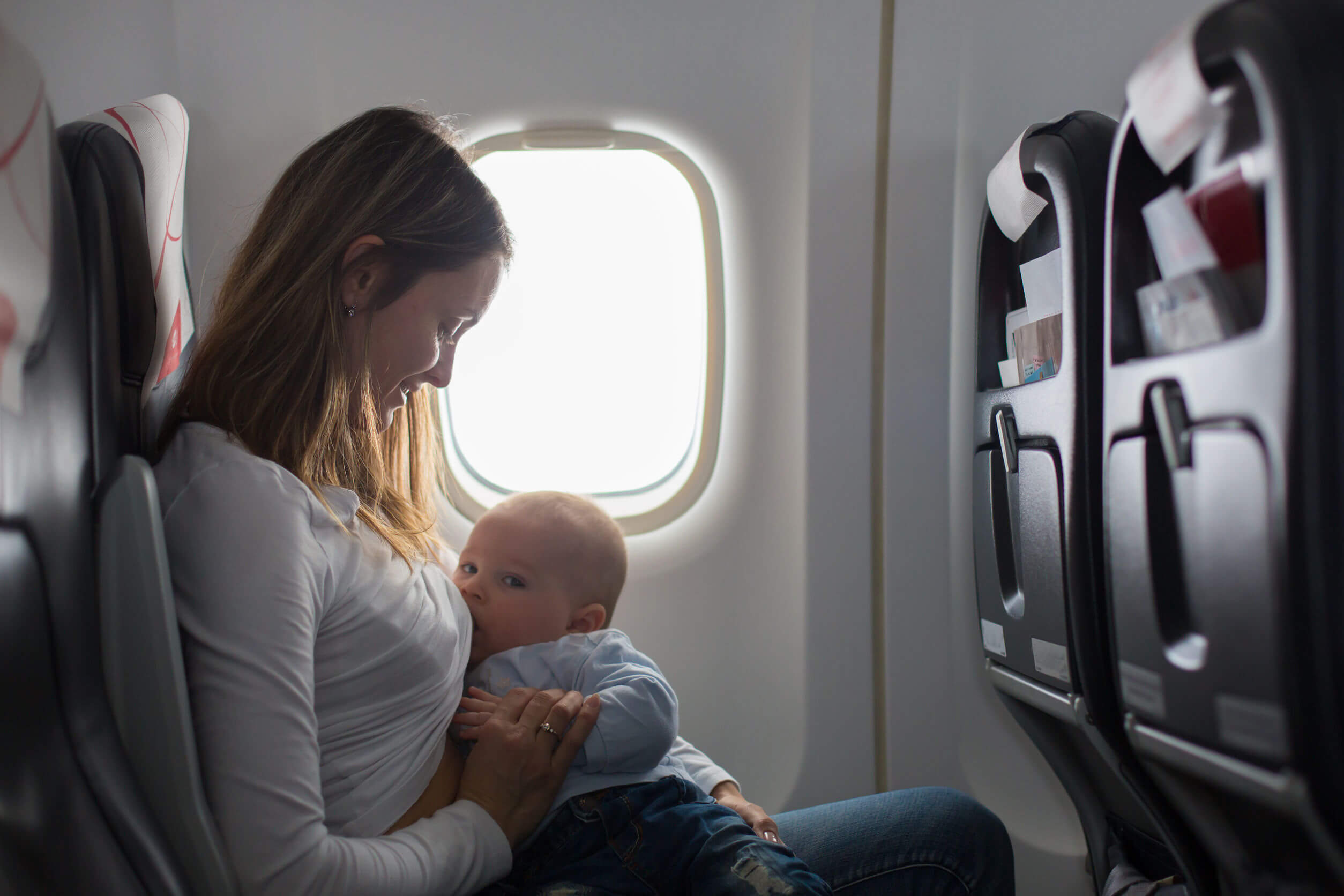 Mujer da pecho a su hijo en un avión.