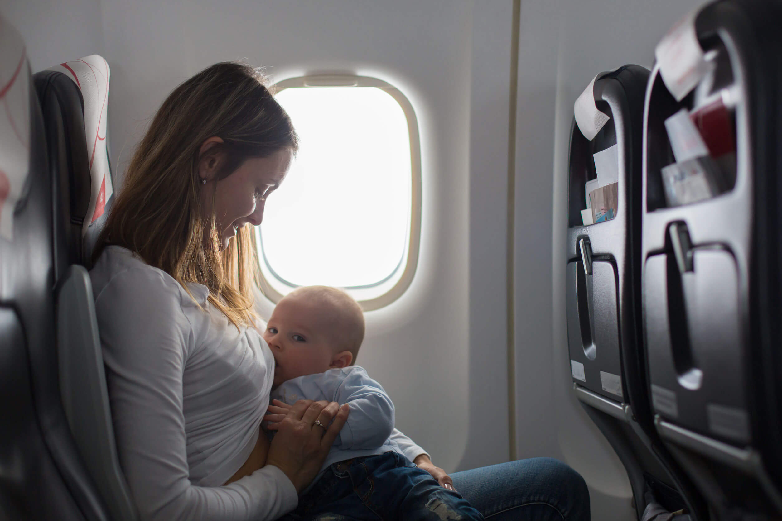 La donna allatta suo figlio su un aeroplano.