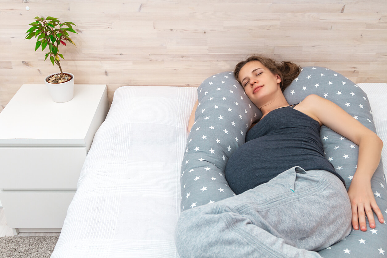 Femme enceinte allongée avec le soutien d'un coussin de grossesse.