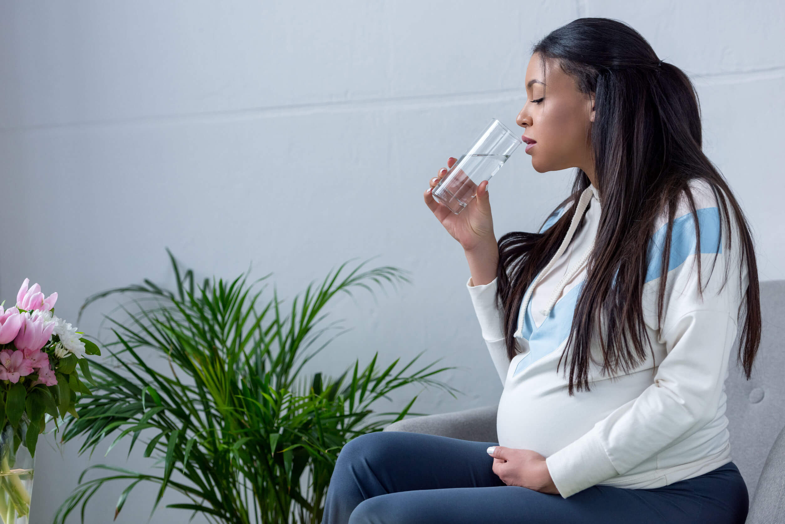 Mujer embarazada bebiendo un vaso de agua.