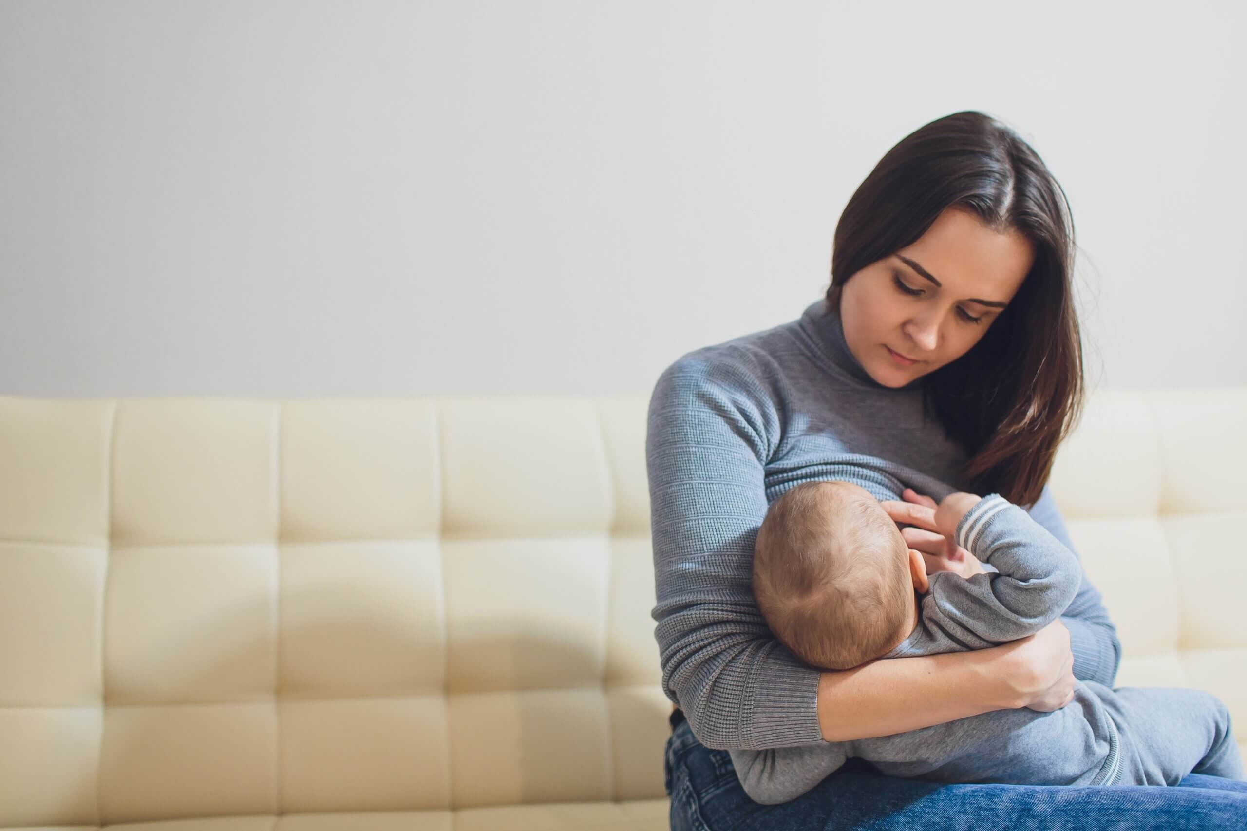 Madre pensando en las frases sobre lactancia materna mientras da el pecho a su hijo.