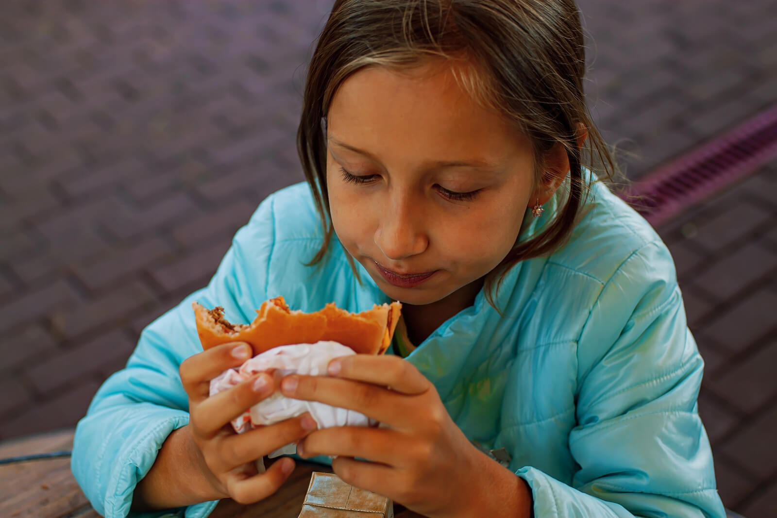 Niña comiéndose una hamburguesa.